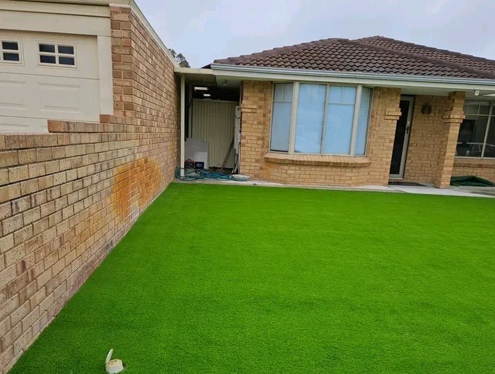 Front yard of a brick house covered in artificial grass, installed by Nulook Landscaping