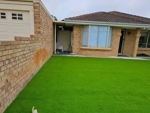 Front yard of a brick house covered in artificial grass